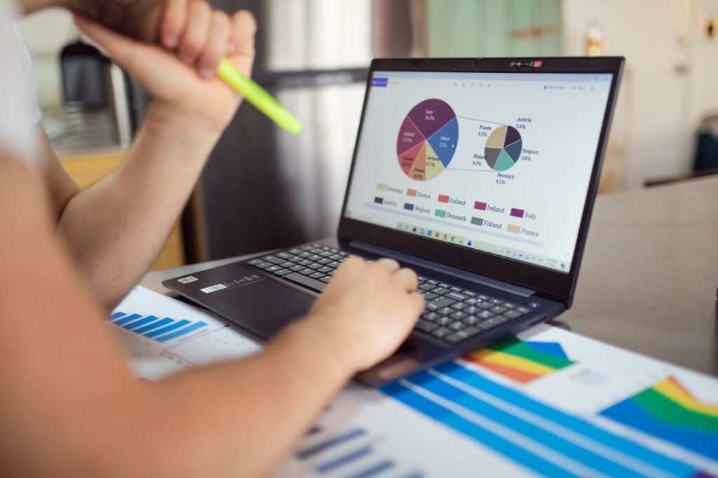 Crafting Captivating Headlines: Your awesome post title goes here Person analyzing financial charts and graphs on a laptop with colorful documents, showcasing market analysis.