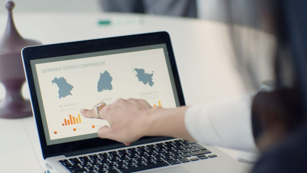 Mastering the First Impression: Your intriguing post title goes here A woman pointing at a laptop screen showing a state comparison chart at a business desk.